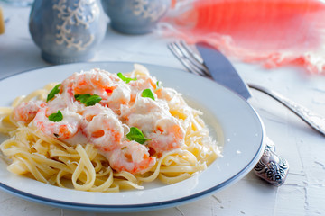 Italian pasta fettuccine in a creamy sauce with shrimp close-up on a plate. horizontal