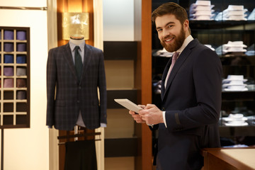 Cheerful man in suit with tablet in wood room