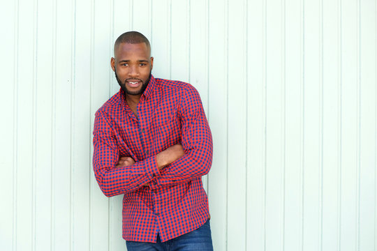 stylish young african man with arms crossed standing by wall