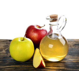 Apple cider vinegar in glass bottle and ripe fresh apples, on wooden table,  on a white background