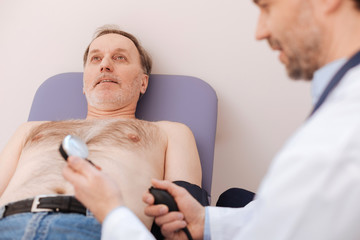 Careful qualified doctor doing patients blood pressure