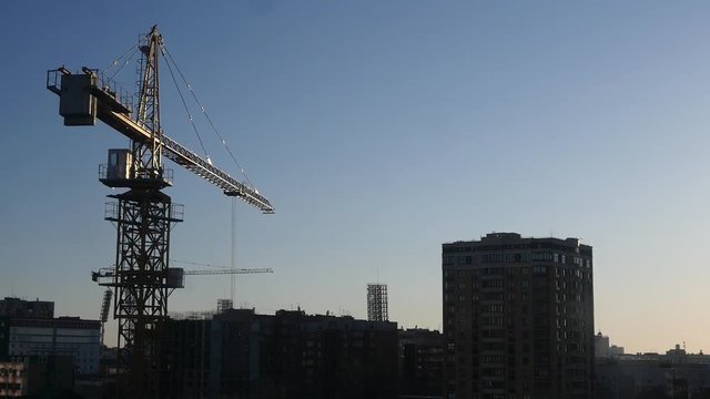 Large building crane in the city on the background of houses and sky in the rays of the passing sun. HD, 1920x1080.
