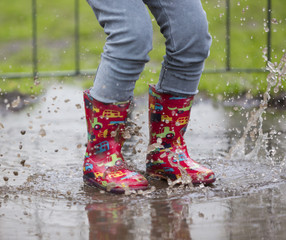 dziecko w kaloszach bawiące się w deszczu - obrazy, fototapety, plakaty