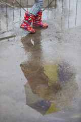 dziecko w kaloszach bawiące się w deszczu - obrazy, fototapety, plakaty