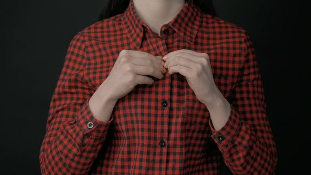 Woman in bra unbuttoning plaid shirt