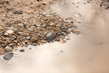 Puddle on the road with stones as background
