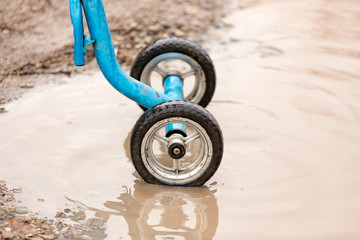Children's bicycle wheels in a puddle on the road