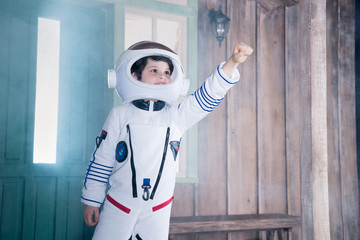 boy in astronaut costume flying on porch - obrazy, fototapety, plakaty