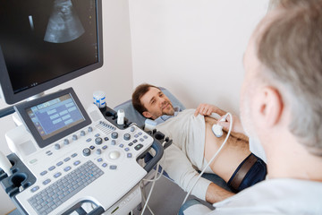 Methodical determined doctor scanning young mans organs