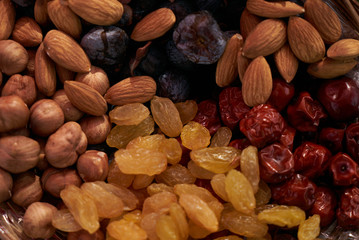 Large collection of nuts, seeds and dried fruits in brown wooden bowls isolated on a golden background