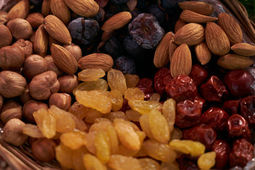 Large collection of nuts, seeds and dried fruits in brown wooden bowls isolated on a golden background