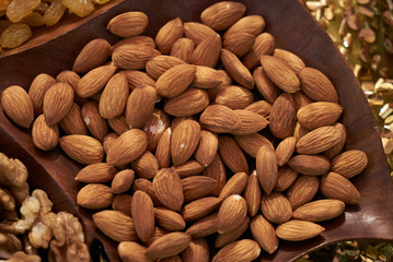 Close-up of Almonds in a brown bowl on wooden background. Almond kernels