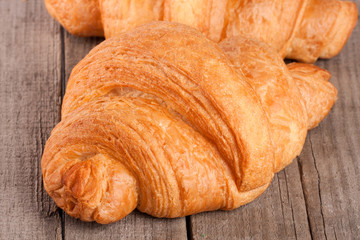 one croissant on old wooden board closeup