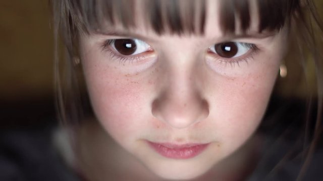 Night shot of kid's girl face browsing tablet pc with light reflection on it