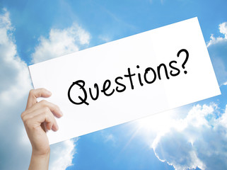 Questions? Sign on white paper. Man Hand Holding Paper with text. Isolated on sky background
