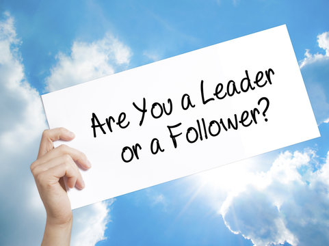 Are You a Leader or a Follower? Sign on white paper. Man Hand Holding Paper with text. Isolated on sky background