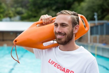Male lifeguard carrying rescue can at poolside