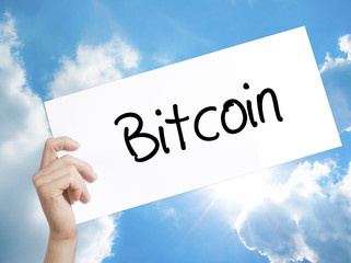 Bitcoin Sign on white paper. Man Hand Holding Paper with text. Isolated on sky background.