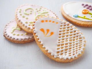 Pile of Easter sugar cookies glazed with royal icing. Ester treat upon rustic table. Beautiful biscuits in the shape of easter egg. Selective focus.