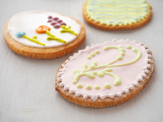 Easter sugar cookies with floral ornament. Homemade cookies glazed with royal icing. Ester treat upon rustic table. Beautiful biscuits in the shape of easter egg. Selective focus.