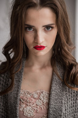 Model in elegant dress and woollen cardigan posing on white baroque interior background