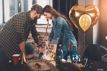 man and woman cleaning messy room after party