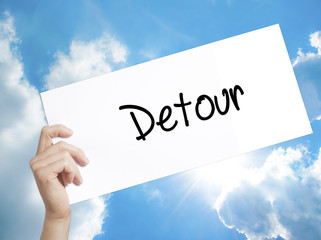 Detour  Sign on white paper. Man Hand Holding Paper with text. Isolated on sky background
