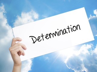Determination  Sign on white paper. Man Hand Holding Paper with text. Isolated on sky background
