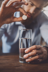 man with hangover with medicines in messy room after party