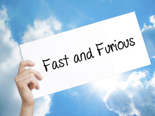 Fast and Furious Sign on white paper. Man Hand Holding Paper with text. Isolated on sky background