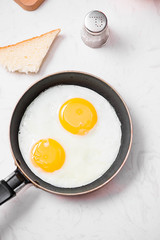 Top view of traditional healthy easy quick breakfast meal made of fried eggs served on a frying pan.