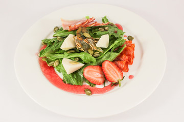 Mix of hot sausages with bacon on a cushion of lettuce leaves, in a duet with parmesan and strawberries, garnished with pumpkin seeds, dressed with raspberry sauce