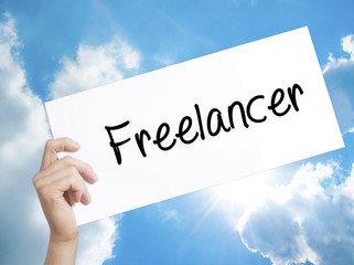 Freelancer Sign on white paper. Man Hand Holding Paper with text. Isolated on sky background.