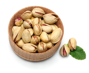 pistachio in wood plate with green leaf isolated on the white background