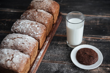 Bread with flour on wooden table with milk and cookie