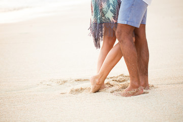 Close-up of couples legs in sand