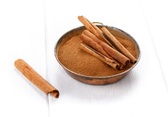 Cinnamon sticks and powder on white table.