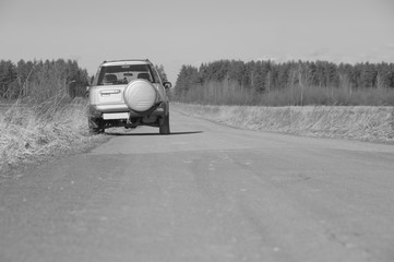 black and white, off-road car on a deserted road.