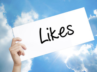 Likes Sign on white paper. Man Hand Holding Paper with text. Isolated on sky background