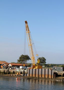 grue enfon&ccedil;ant des palplanches en m&eacute;tal dans la vase du port  par vibration
