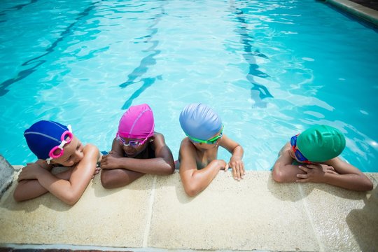 Little swimmers talking while leaning at poolside