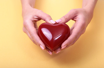 Female hands giving red heart, isolated on gold background