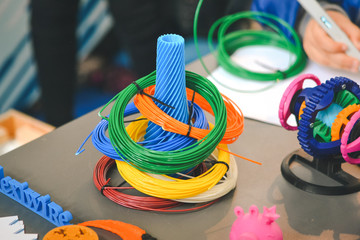 Figure and Skeins of Plastic for 3D printer. Production printed by 3d printer on table close-up.