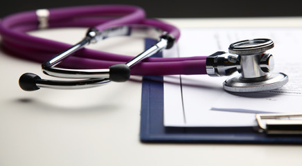 Stethoscope with cardiogram lying on desk in hospital