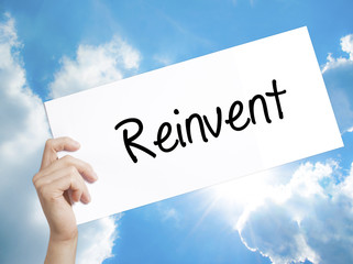  Reinvent Sign on white paper. Man Hand Holding Paper with text. Isolated on sky background