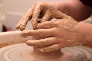 Hands of a potter, creating an earthen jar on pottery wheel.