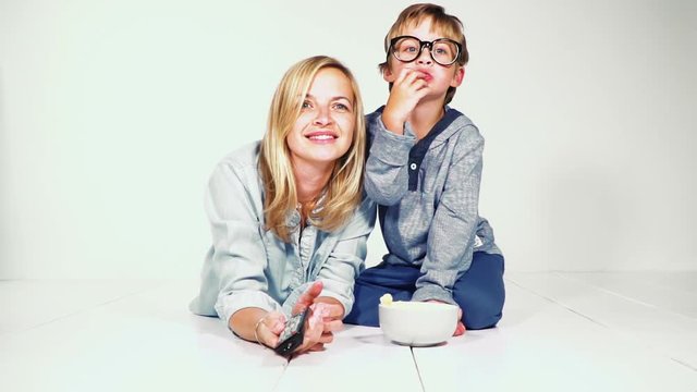 mutter und sohn liegen am boden und essen maisstangerl und schauen fern