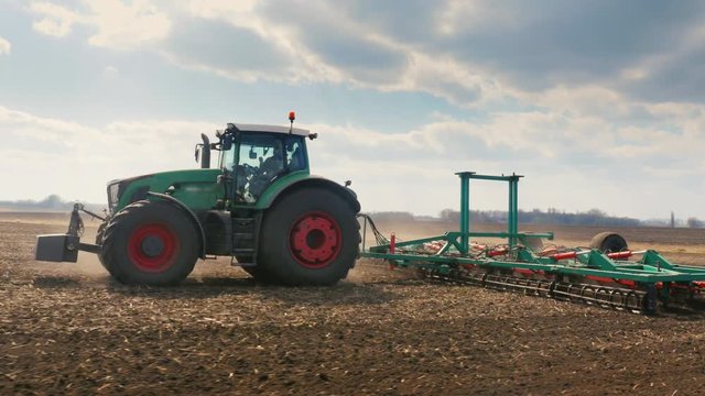 Tracking shot: tractor Plows the land in the field. Spring field works. Beautiful sunny day in good weather. 3-axis stabilized video