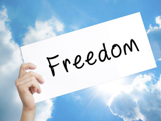 Freedom Sign on white paper. Man Hand Holding Paper with text. Isolated on sky background