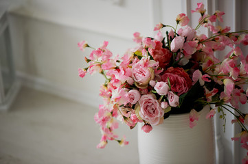 Artificial spray roses pink pastel colors in a white vase.